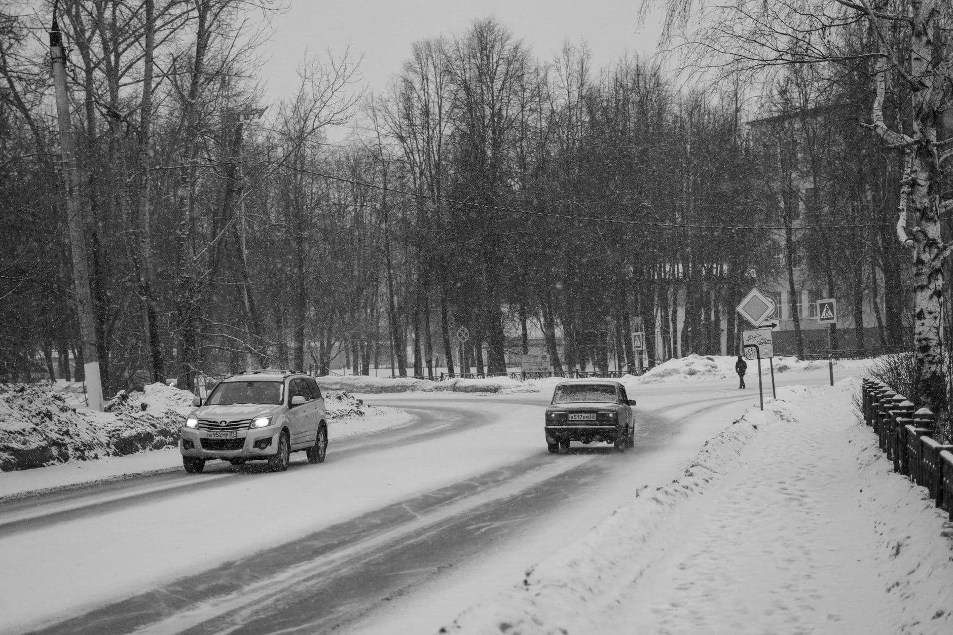 Bilar kör försiktigt på snöig vinterväg — vinterkörning och halkbaneutbildning.